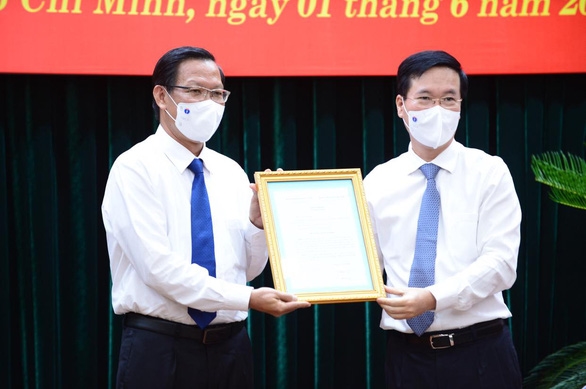 El miembro permanente del Secretariado del Partido, Vo Van Thuong, entrega la Decisión del nombramiento al nuevo vicesecretario permanente del Comité partidista de Ciudad Ho Chi Minh, Phan Van Mai.