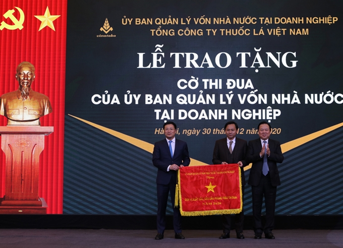 El presidente del Comité de Gestión de capitales estatales en las empresas, Nguyen Hoang Anh, entregó la bandera de emulación al grupo general del Tabaco.