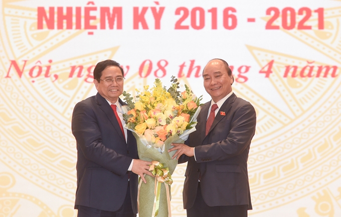 El presidente de Vietnam, Nguyen Xuan Phuc (d.) felicita al primer ministro Nguyen Xuan Phuc, en la ceremonia.